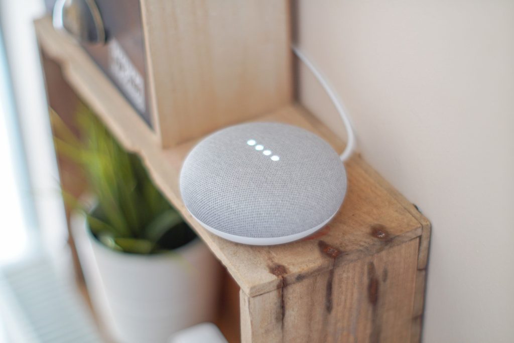Google Home Mini smart speaker on a wooden shelf