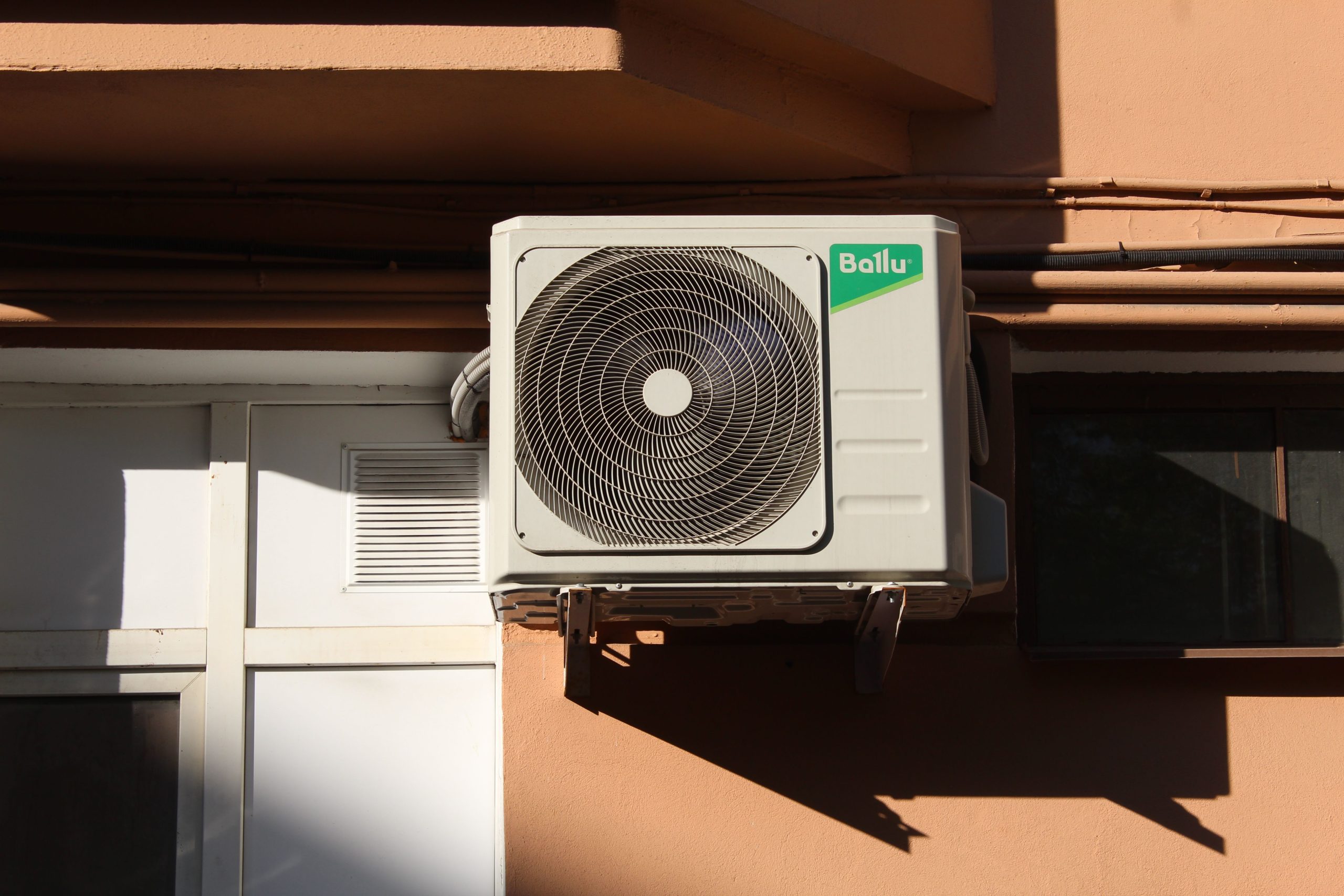Air conditioner condenser unit mounted on a residential wall