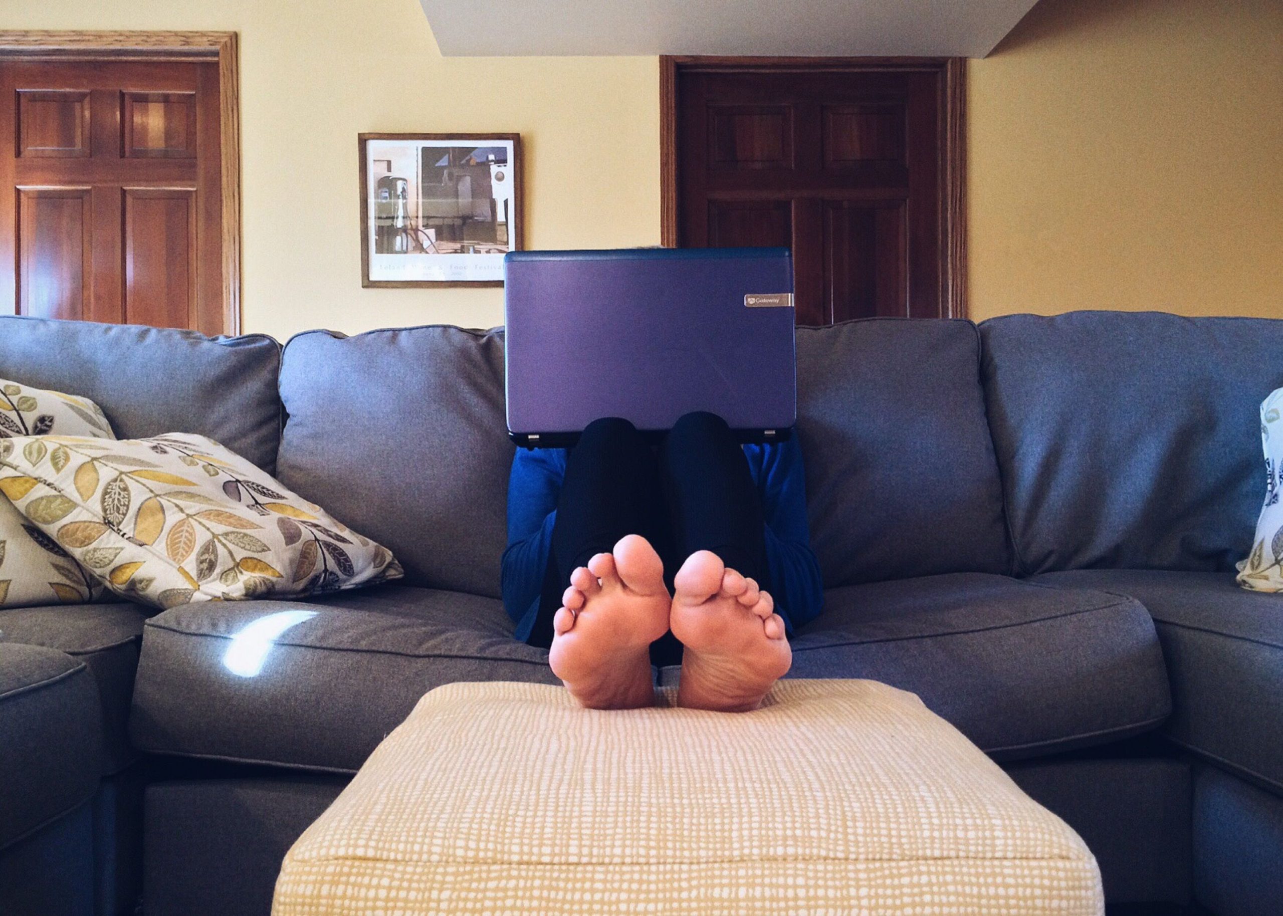 Person relaxing on a couch streaming on a laptop at home