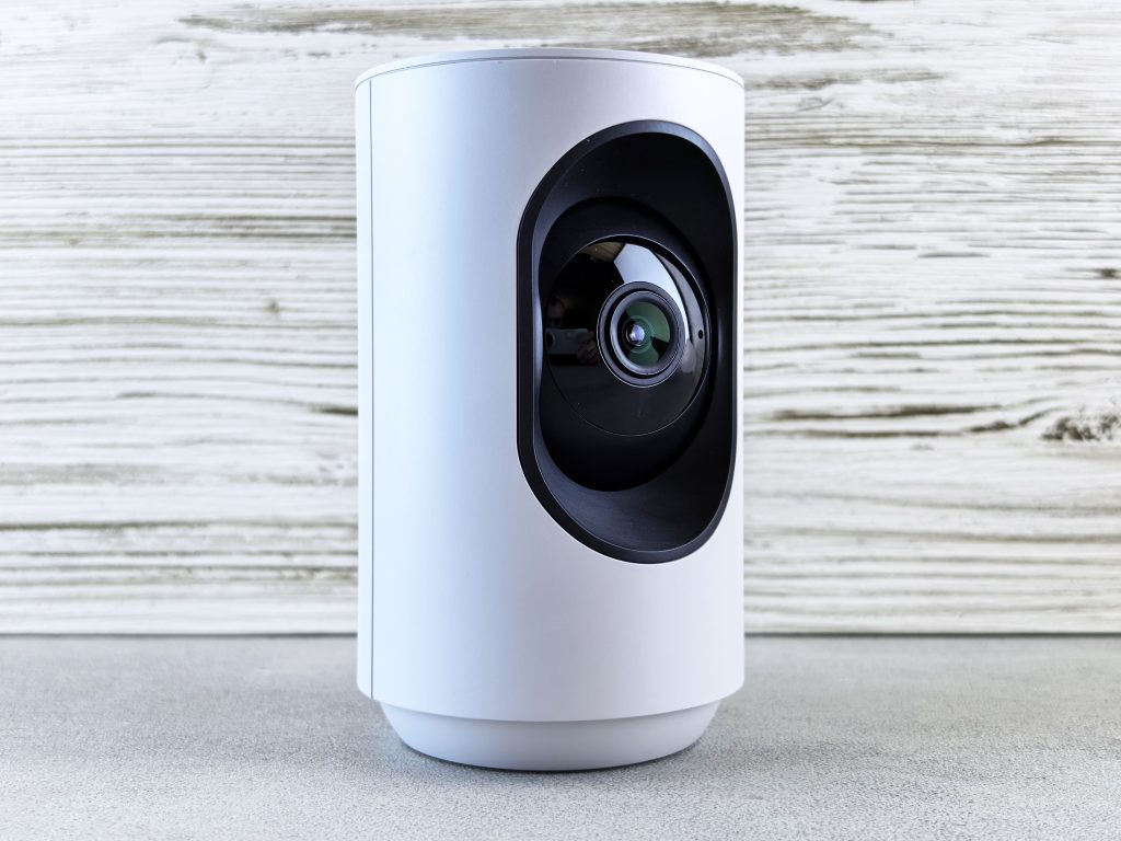 White indoor security camera on a wooden surface