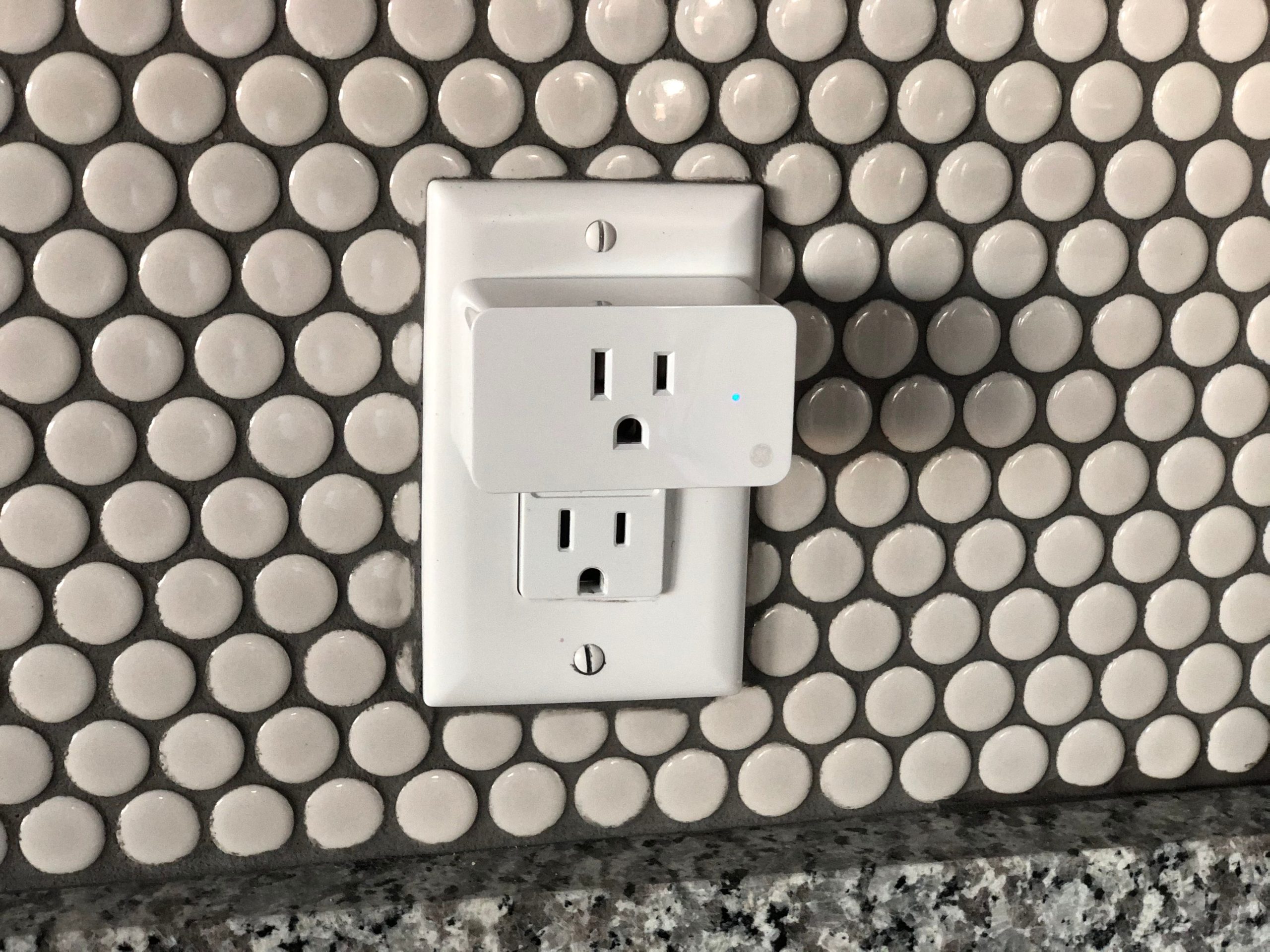 Close-up of a smart plug on a tiled wall