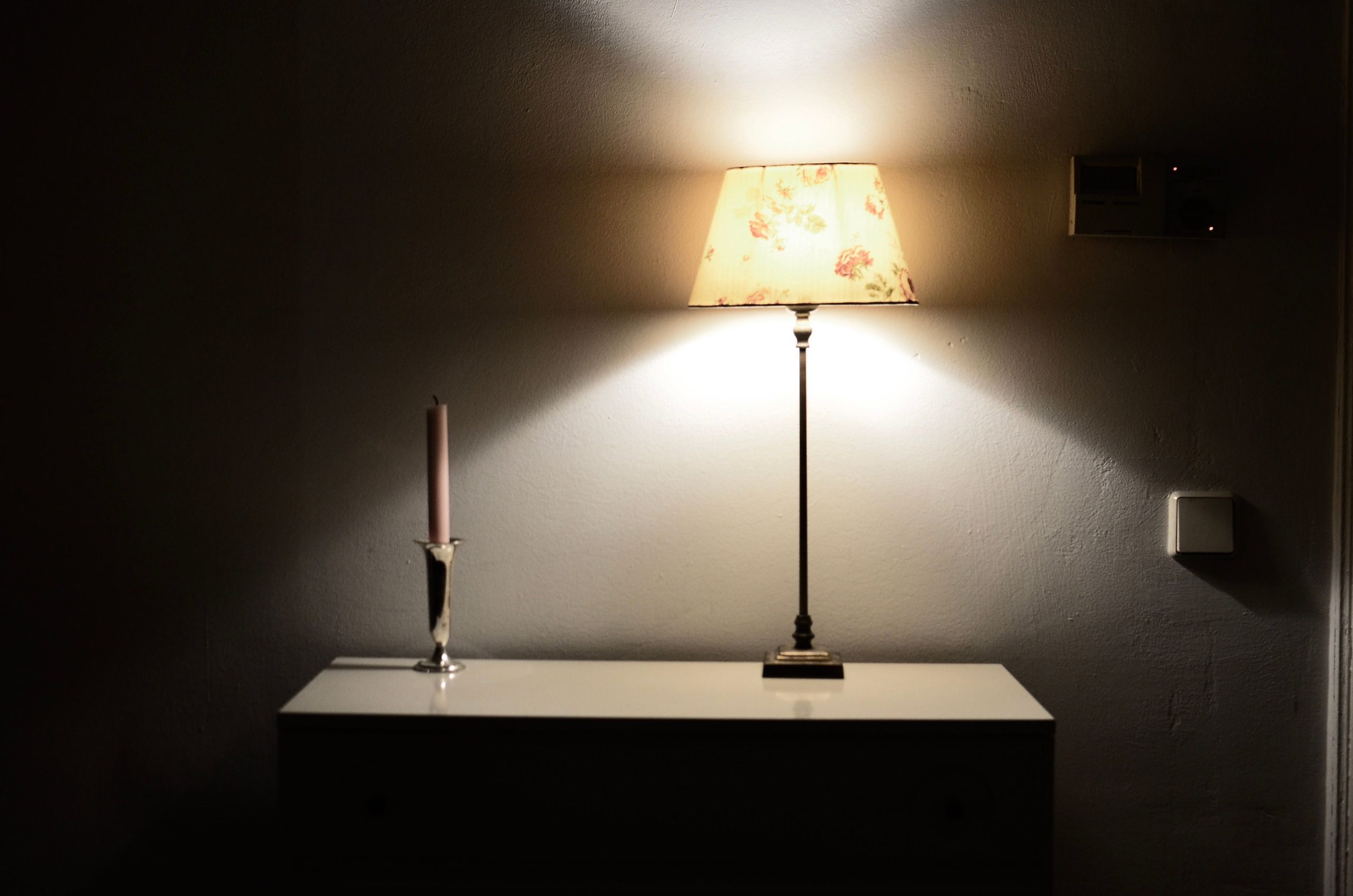 Warm glowing lamp beside a candle in a cozy room